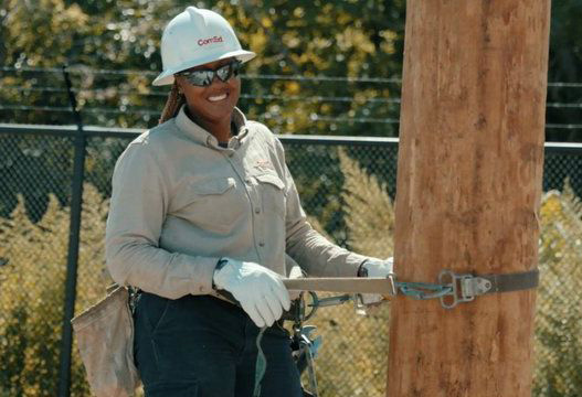 Woman in hard hat inspecting a telephone pole