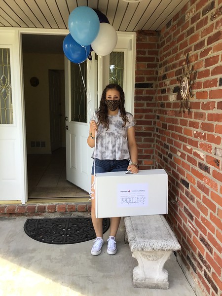 Student in mask holding balloons and carrying case