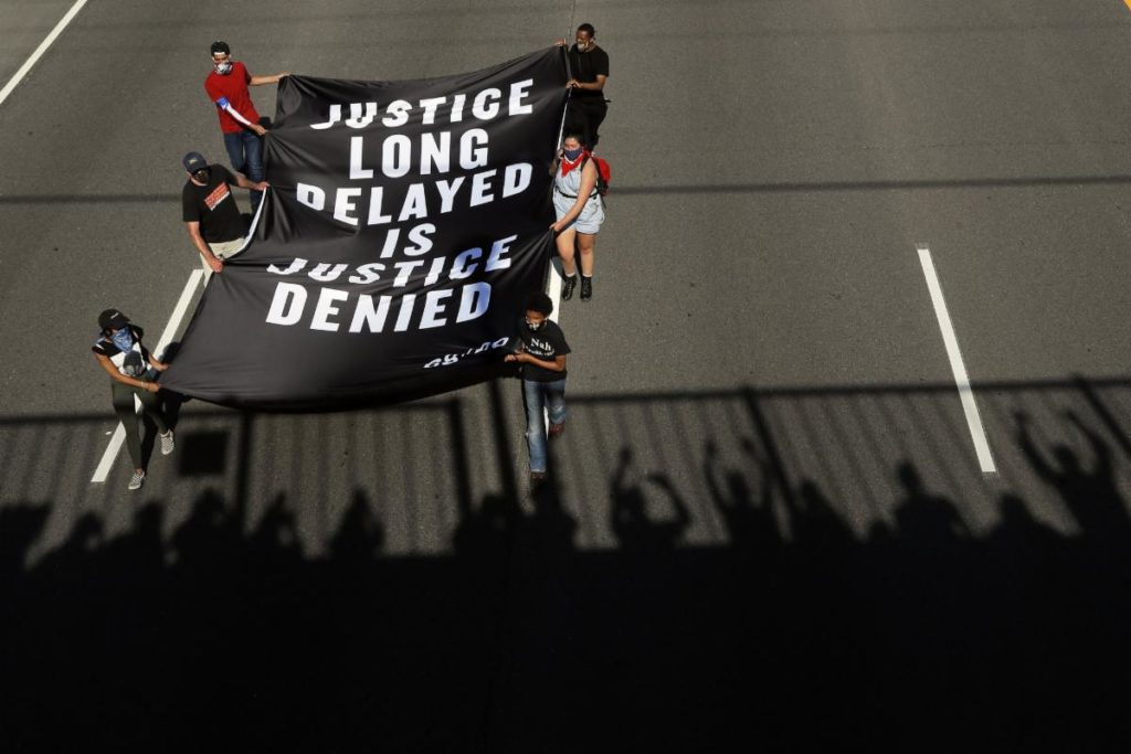 Students holding a "Justice long delayed is justice denied" banner